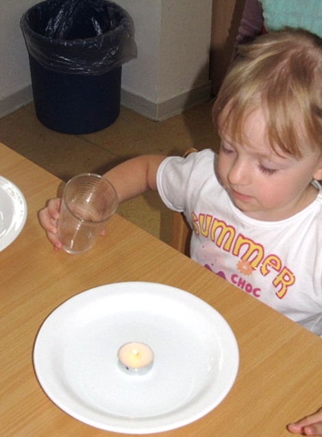 Ein Kind erforscht den Zusammenhang zwischen Kerzenlicht und Luftzufuhr.