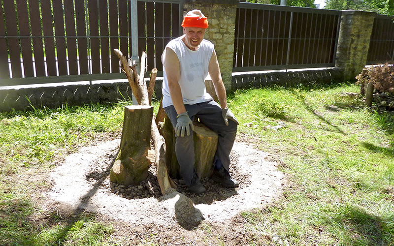 Ein Mann sitzt auf den Holzstämmen