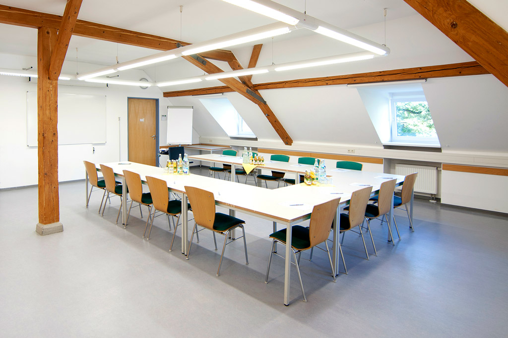 Seminarraum mit Holzbalken, Dachschräge, Tische in U-Form gestellt