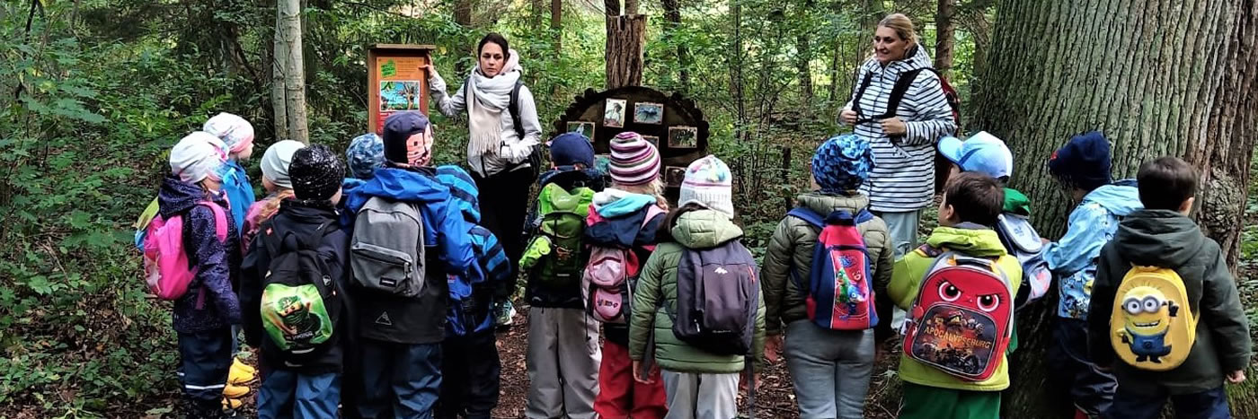 Viele Kinder und zwei Erzieherinnen im Wald