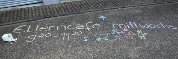 Ein Kreidebild auf der Straße. Text: Elterncafé mittwochs 9:30-11:30 Uhr